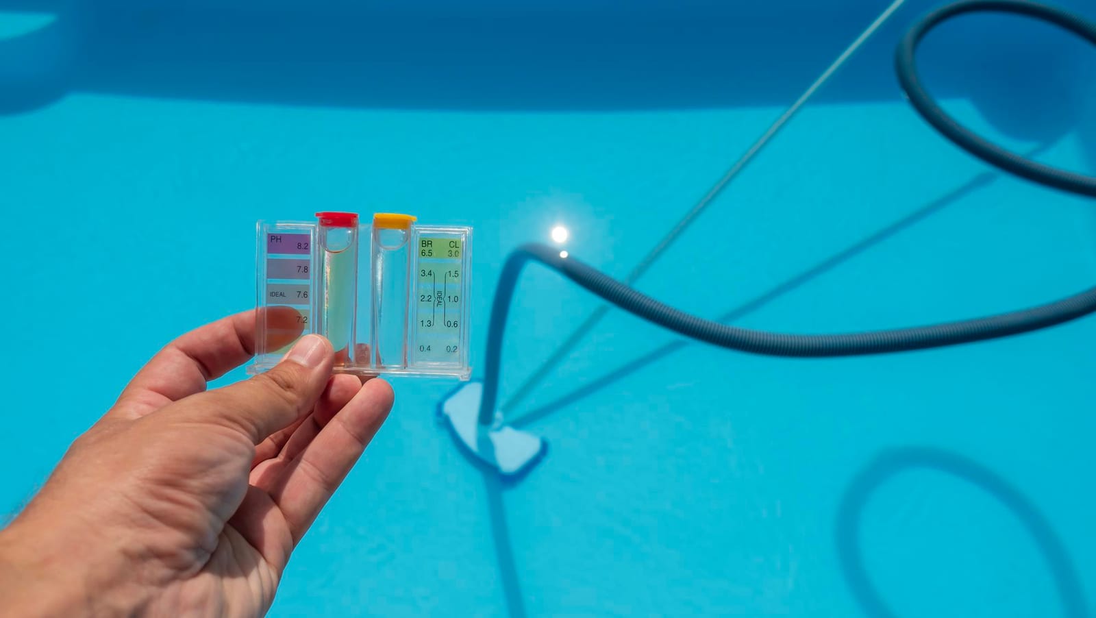 A technician dipping a water-testing kit into a clear residential pool during a diagnostic visit