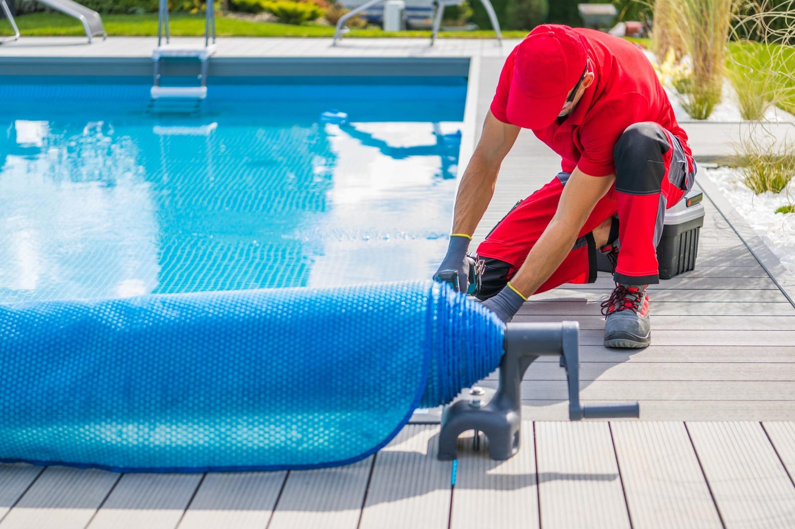 A technician finishing a pool deck installation near the equipment pad after a repair visit